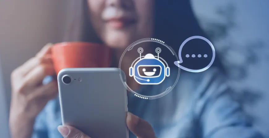 Foto: Person hält ein Smartphone, daneben ein Chatbot-Symbol mit Sprechblase